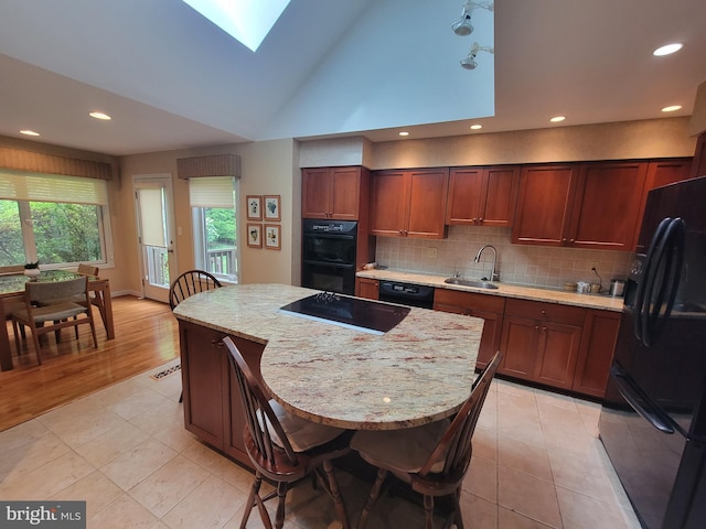 7 E Cardiff Ct, Newark, DE 19711 - kitchen with black appliances, a skylight, backsplash, a center island, and light tile patterned floors