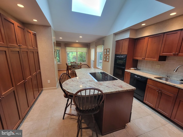 7 E Cardiff Ct, Newark, DE 19711 - kitchen featuring black appliances, a breakfast bar, light tile patterned flooring, a skylight, and decorative backsplash