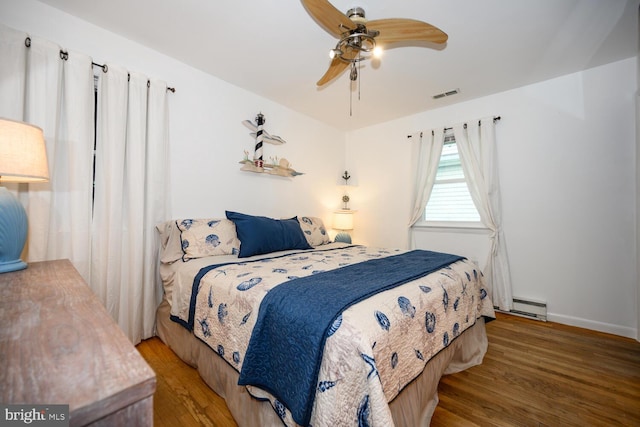 644 Chester River Beach Rd, Grasonville, MD 21638 - bedroom with wood finished floors, a baseboard radiator, and a ceiling fan