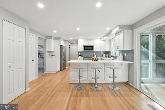 6 Ivywood Ct, Silver Spring, MD 20904 - kitchen with stainless steel appliances, a peninsula, light wood-style floors, white cabinets, and light countertops