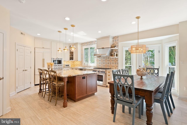 10915 Lamplighter Ln, Potomac, MD 20854 - kitchen featuring built in appliances, extractor fan, decorative backsplash, a kitchen island, and light stone countertops