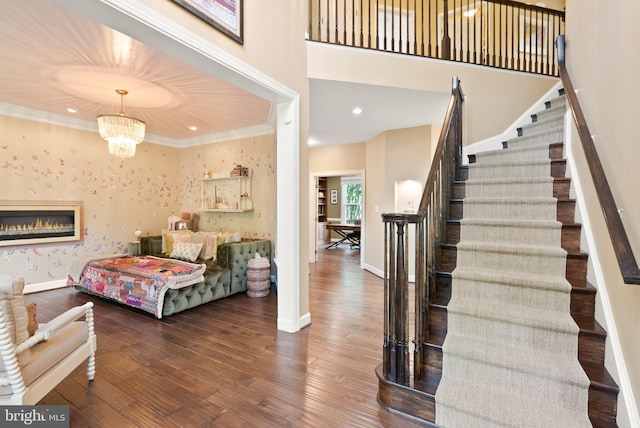 10915 Lamplighter Ln, Potomac, MD 20854 - stairway featuring wood finished floors, ornamental molding, a chandelier, recessed lighting, and a glass covered fireplace
