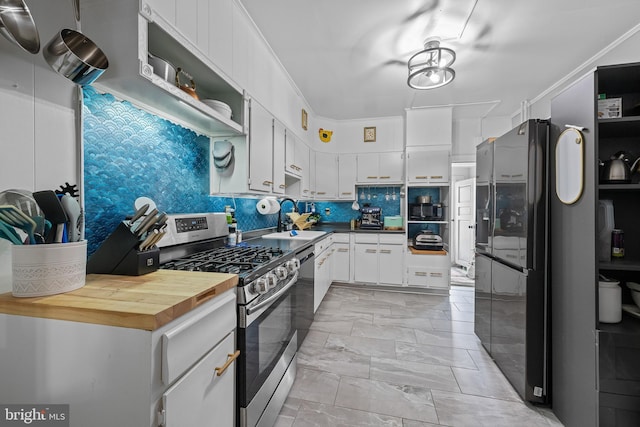 1105 Brown St, Wilmington, DE 19805 - kitchen featuring stainless steel appliances, white cabinetry, backsplash, butcher block counters, and light marble finish flooring
