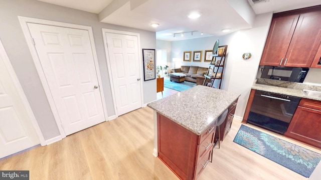 960 Fell St Unit 609, Baltimore, MD 21231 - kitchen featuring black appliances, light wood-type flooring, light stone countertops, and a kitchen island