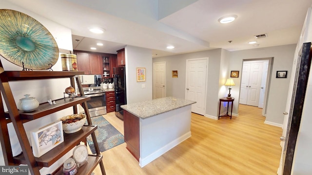 960 Fell St Unit 609, Baltimore, MD 21231 - kitchen with stainless steel electric range, freestanding refrigerator, light wood-type flooring, light stone countertops, and a kitchen island