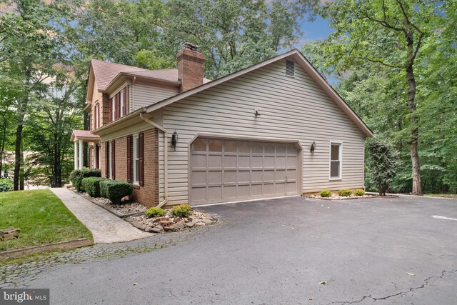 12779 Lost Creek Ct, Manassas, VA 20112 - view of home's exterior with a chimney, brick siding, asphalt driveway, and an attached garage