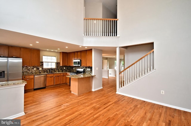316 Wheatfield Cir, Hatfield, PA 19440 - kitchen featuring stainless steel appliances, light wood finished floors, decorative backsplash, a peninsula, and brown cabinets