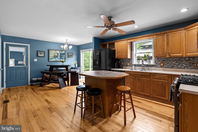 613 Main St, Langhorne, PA 19047 - kitchen with gas range, black fridge, decorative backsplash, light wood-type flooring, and brown cabinetry