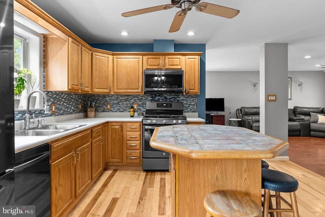613 Main St, Langhorne, PA 19047 - kitchen with appliances with stainless steel finishes, light wood-type flooring, ceiling fan, a breakfast bar area, and backsplash