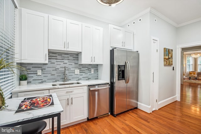 609 Elliott St NE, Washington, DC 20002 - kitchen featuring appliances with stainless steel finishes, crown molding, tasteful backsplash, light wood-style floors, and white cabinets