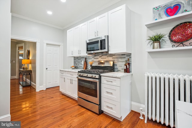 609 Elliott St NE, Washington, DC 20002 - kitchen with stainless steel appliances, radiator, crown molding, decorative backsplash, and white cabinets