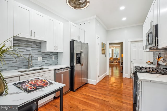 609 Elliott St NE, Washington, DC 20002 - kitchen featuring appliances with stainless steel finishes, light wood-style floors, white cabinetry, crown molding, and backsplash