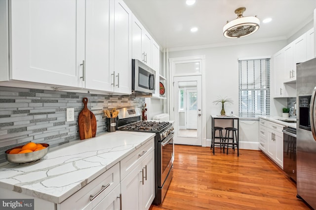 609 Elliott St NE, Washington, DC 20002 - kitchen with stainless steel appliances, healthy amount of natural light, ornamental molding, tasteful backsplash, and white cabinets