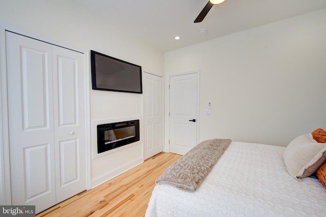 921 S Conestoga St, Philadelphia, PA 19143 - bedroom with light wood-style floors, multiple closets, a glass covered fireplace, recessed lighting, and ceiling fan
