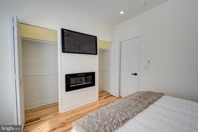 921 S Conestoga St, Philadelphia, PA 19143 - bedroom with two closets, wood finished floors, a glass covered fireplace, and recessed lighting