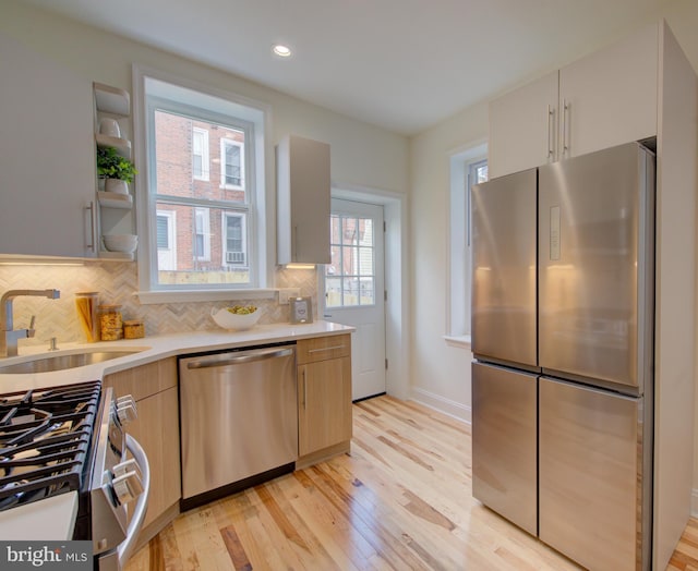921 S Conestoga St, Philadelphia, PA 19143 - kitchen with appliances with stainless steel finishes, light countertops, light wood-style floors, backsplash, and recessed lighting