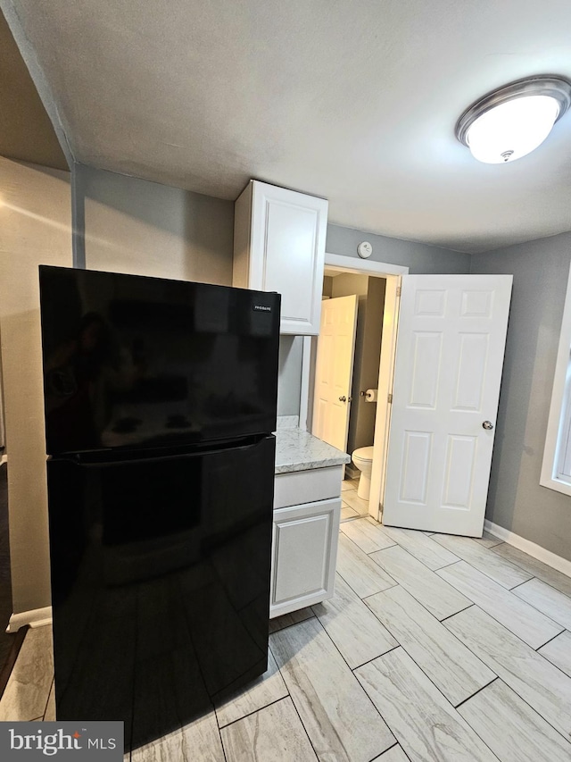 18 N 5th St, Columbia, PA 17512 - kitchen with freestanding refrigerator, white cabinets, and light stone counters