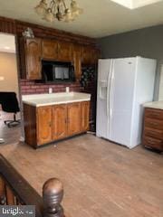 7128 Crestshire, Baltimore, MD 21222 - kitchen featuring white refrigerator with ice dispenser, black microwave, light countertops, brown cabinets, and light wood-style flooring