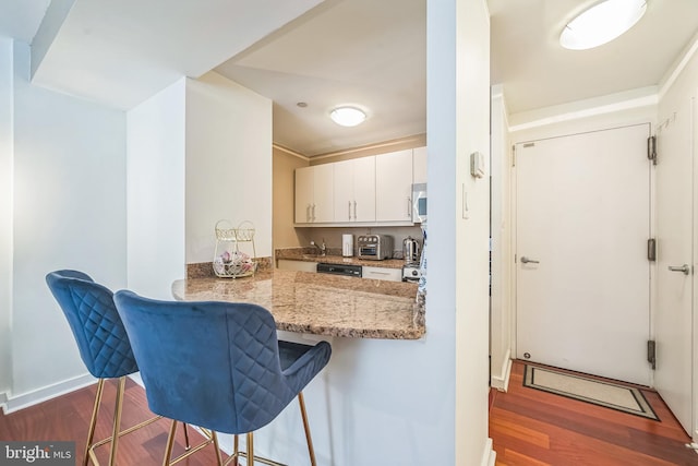 219 S 18th St Unit 1522, Philadelphia, PA 19103 - kitchen with stainless steel microwave, wood finished floors, a breakfast bar area, and a peninsula