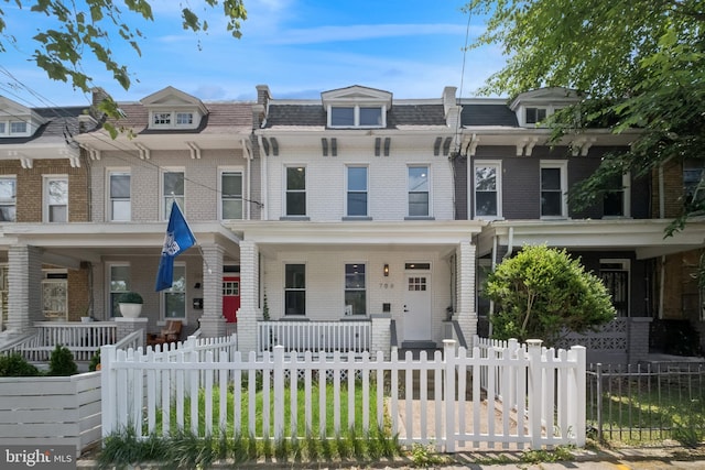 706 Longfellow St NW, Washington, DC 20011 - view of property featuring a porch, mansard roof, brick siding, and a fenced front yard