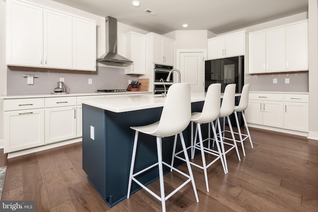 5635 Saucon Ridge Rd, Coopersburg, PA 18036 - kitchen featuring wall chimney range hood, tasteful backsplash, a kitchen bar, white cabinetry, and light countertops