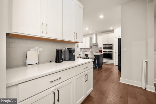 5635 Saucon Ridge Rd, Coopersburg, PA 18036 - kitchen with wall chimney range hood, stainless steel double oven, white cabinetry, dark wood-style flooring, and recessed lighting