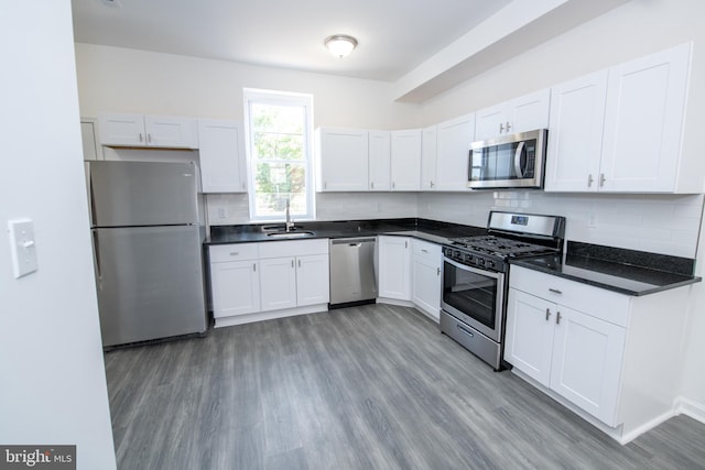 1615 Rowan St, Philadelphia, PA 19140 - kitchen featuring stainless steel appliances, dark countertops, wood finished floors, and decorative backsplash