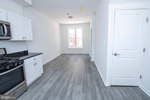 1615 Rowan St, Philadelphia, PA 19140 - kitchen with appliances with stainless steel finishes, wood finished floors, white cabinets, and backsplash