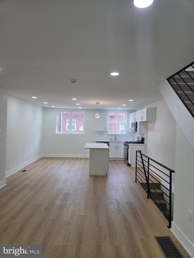 1473 Stevens St, Philadelphia, PA 19149 - kitchen with range with gas cooktop, white cabinets, stainless steel microwave, a center island, and light wood-type flooring