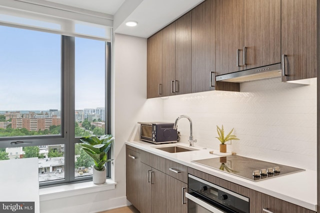 1211 Van St SE Unit 913, Washington, DC 20003 - kitchen with wall oven, tasteful backsplash, black electric cooktop, under cabinet range hood, and light countertops