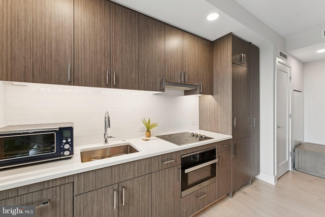 1211 Van St SE Unit 913, Washington, DC 20003 - kitchen featuring black appliances, light countertops, backsplash, light wood finished floors, and recessed lighting