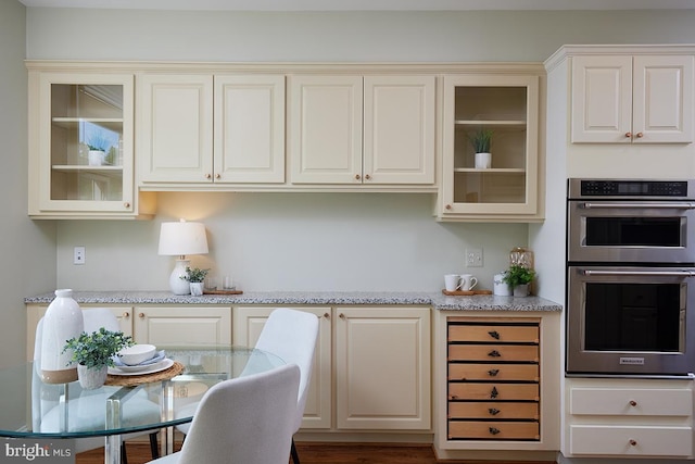 2801 Connecticut Ave NW Unit 32, Washington, DC 20008 - kitchen featuring stainless steel double oven, glass insert cabinets, and light stone counters