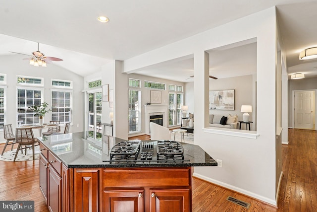5570 La Vista Dr, Alexandria, VA 22310 - kitchen with ceiling fan, black gas stovetop, light wood finished floors, dark stone countertops, and a glass covered fireplace