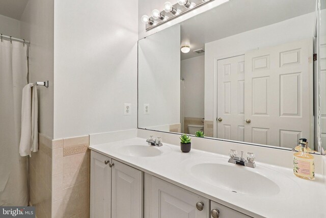 5570 La Vista Dr, Alexandria, VA 22310 - full bathroom featuring double vanity, wainscoting, and tile walls