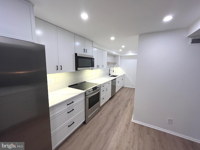 7720 Tremayne Pl Unit 107, Mclean, VA 22102 - kitchen featuring appliances with stainless steel finishes, white cabinets, decorative backsplash, open shelves, and light wood-type flooring