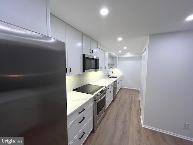 7720 Tremayne Pl Unit 107, Mclean, VA 22102 - kitchen featuring stainless steel appliances, white cabinetry, backsplash, light wood finished floors, and light stone counters