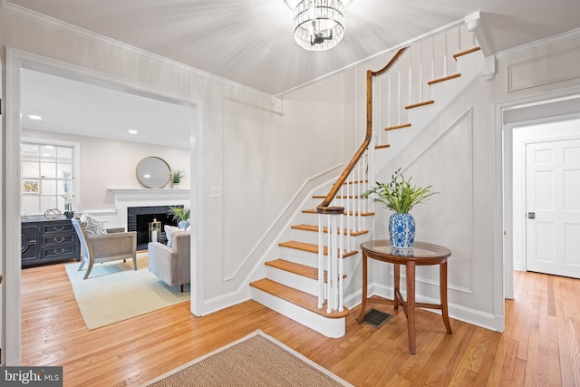 7819 Overbrook, Ruxton, MD 21204 - stairway with wood finished floors, a brick fireplace, ornamental molding, and a chandelier