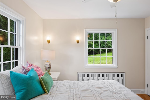 7819 Overbrook, Ruxton, MD 21204 - bedroom featuring radiator heating unit, multiple windows, a ceiling fan, and wood finished floors