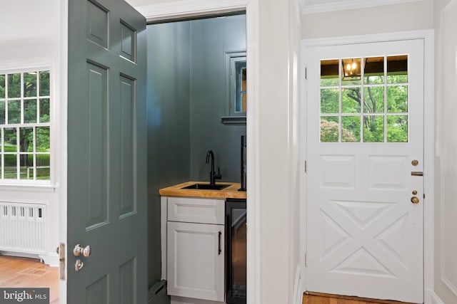 7819 Overbrook, Ruxton, MD 21204 - doorway to outside with radiator, bar with sink, ornamental molding, healthy amount of natural light, and beverage cooler
