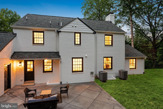 7819 Overbrook, Ruxton, MD 21204 - back of property at dusk with a chimney, a patio, a lawn, and brick siding