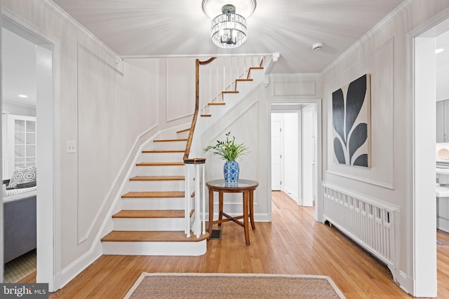 7819 Overbrook, Ruxton, MD 21204 - staircase with radiator heating unit, wood finished floors, crown molding, a decorative wall, and a chandelier