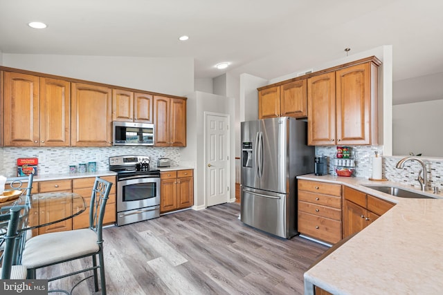3709 Apple Cider Ct, Dumfries, VA 22025 - kitchen with stainless steel appliances, vaulted ceiling, light countertops, tasteful backsplash, and light wood finished floors