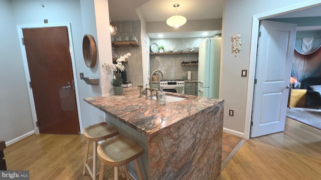 715 6th St NW Unit 1002, Washington, DC 20001 - kitchen with light wood-style floors, open shelves, decorative backsplash, a kitchen breakfast bar, and a peninsula