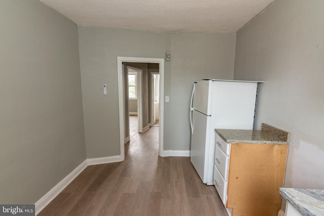 1304 N Linwood Ave, Baltimore, MD 21213 - kitchen with freestanding refrigerator, light wood-style floors, a textured ceiling, and light stone countertops