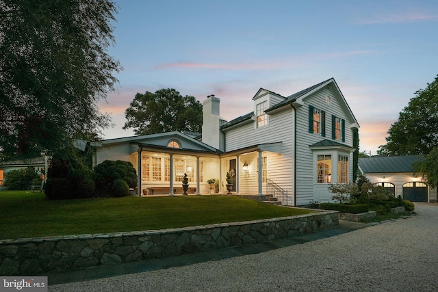 3201/2 Mansion Dr, Alexandria, VA 22302 - back of property at dusk featuring a garage, a yard, a chimney, and driveway