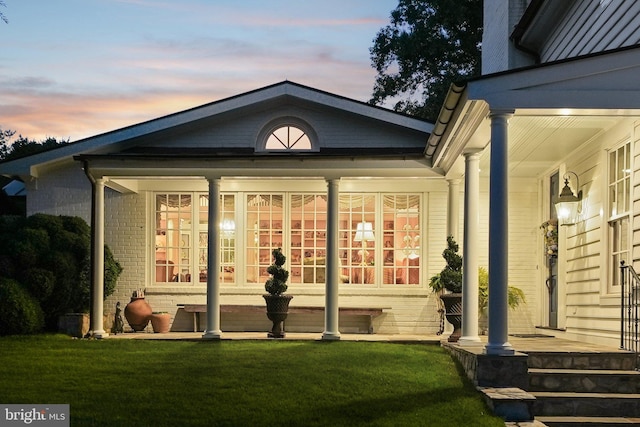 3201/2 Mansion Dr, Alexandria, VA 22302 - exterior entry at dusk featuring a yard, covered porch, and brick siding