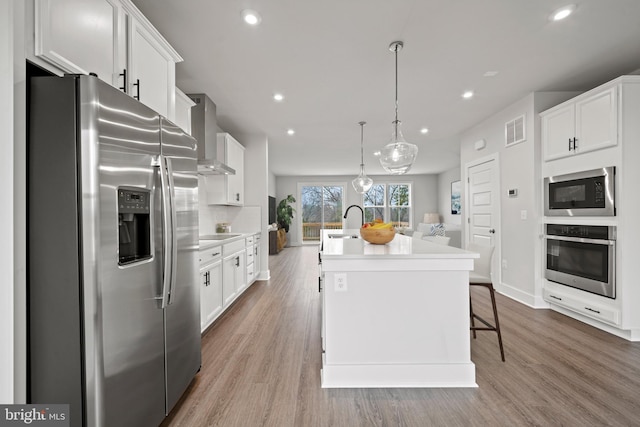 3507 Saint Robin Ln, Bowie, MD 20716 - kitchen featuring appliances with stainless steel finishes, wall chimney exhaust hood, recessed lighting, white cabinetry, and an island with sink