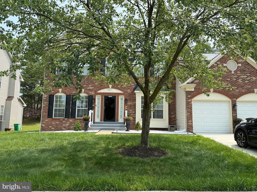 10303 Halton Ter, Lanham, MD 20706 - view of front of house with brick siding, concrete driveway, a front yard, and an attached garage
