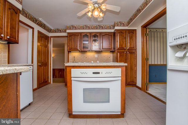 1018 Hilltop Rd, Warminster, PA 18974 - kitchen featuring white appliances, a ceiling fan, light tile patterned floors, tasteful backsplash, and brown cabinetry