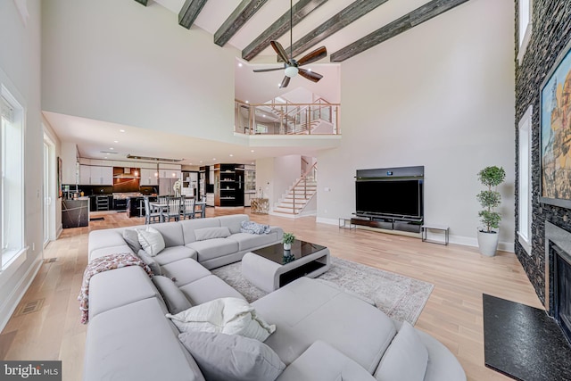 9908 Blake Ln, Oakton, VA 22124 - living room with a towering ceiling, stairway, a fireplace, light wood-style floors, and ceiling fan